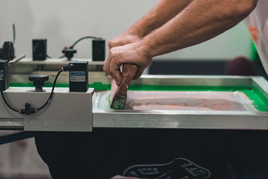 man's hands working on a screen printing machine