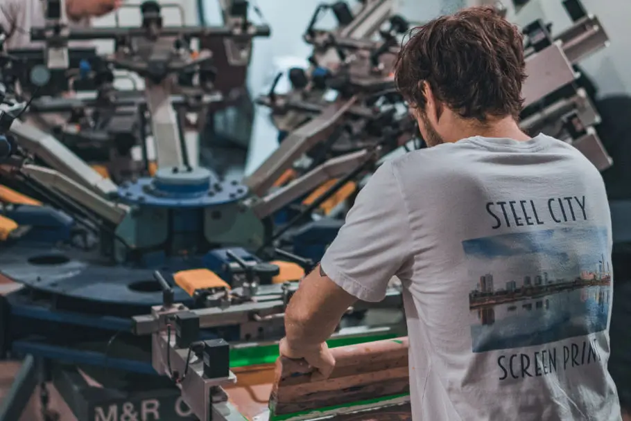 man in white t-shirt working on big screen printing machine