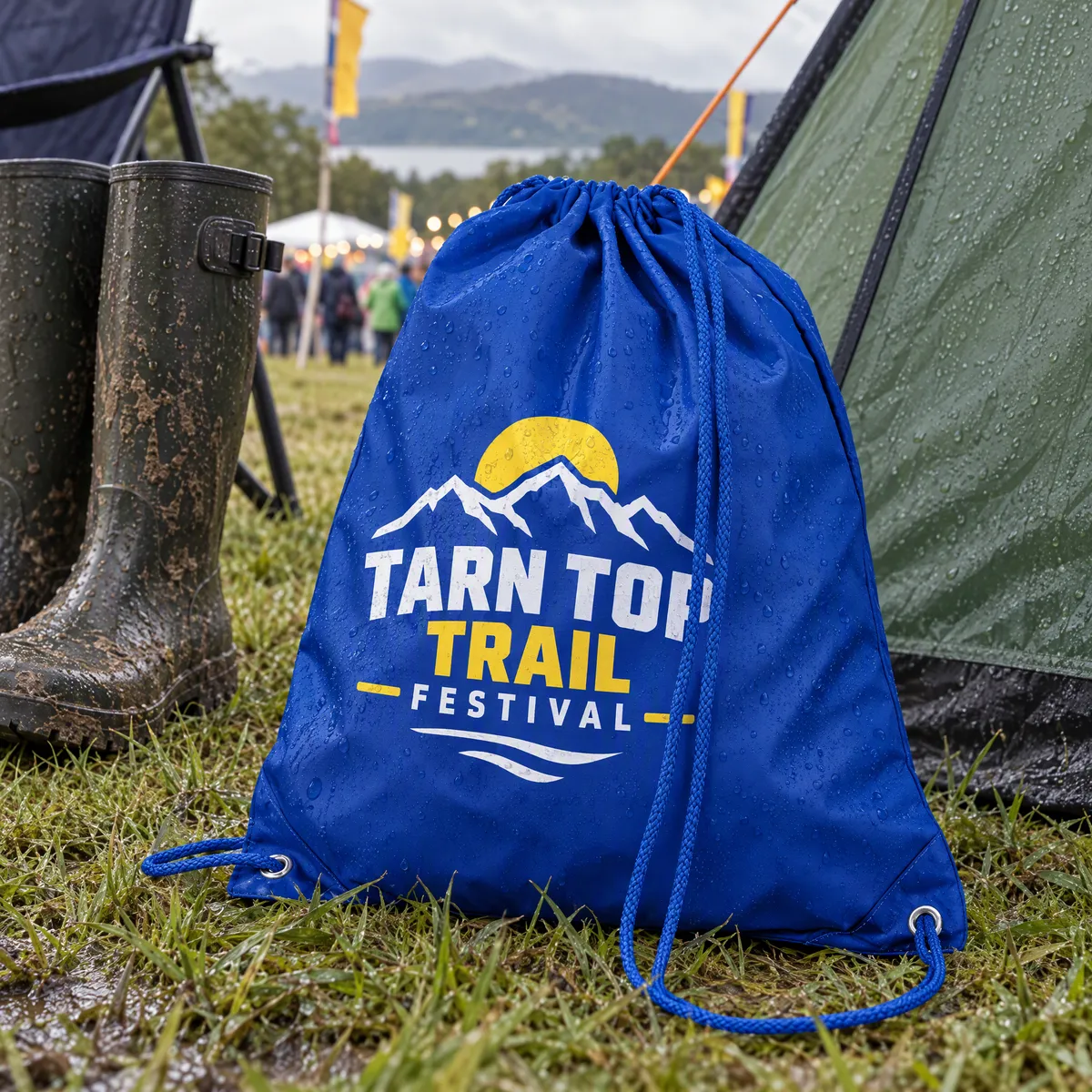 Royal blue polyester drawstring bag printed with a Tarn Top Trail Festival logo, on wet grass outside a tent