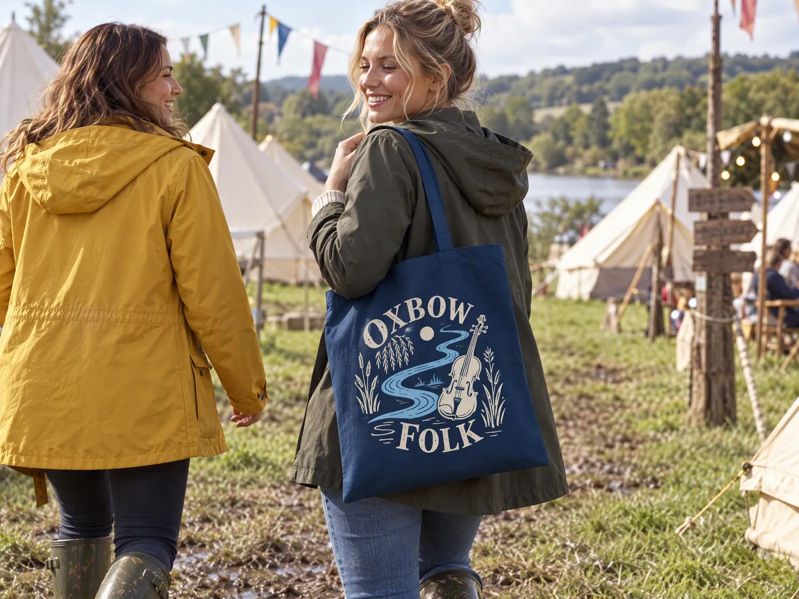 Navy cotton tote printed with an Oxbow Folk Festival design in cream and sky blue, carried through a festival campsite