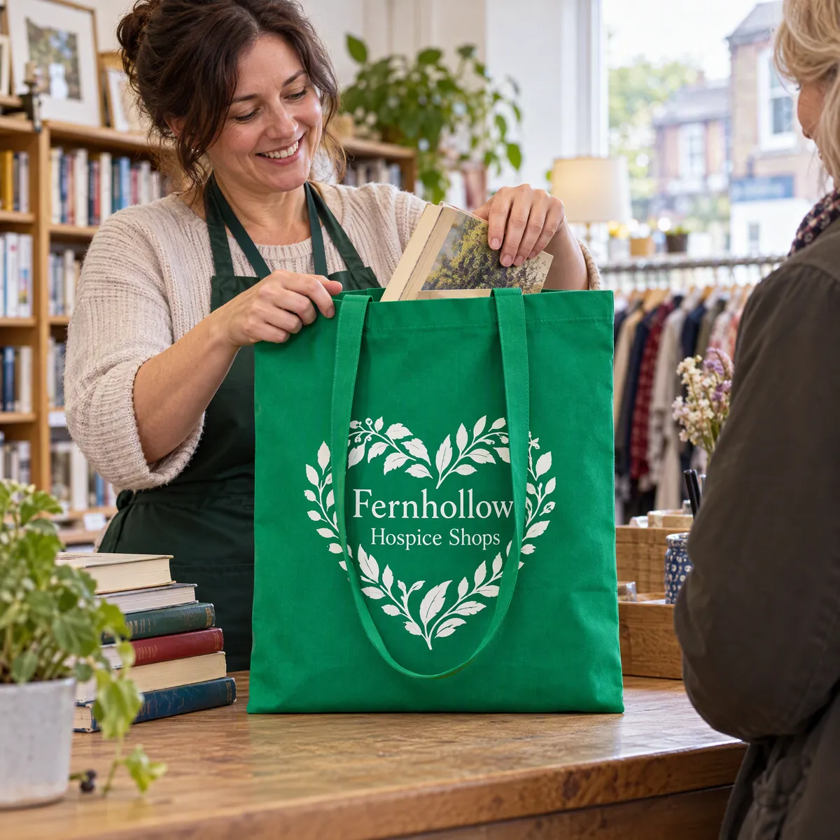 Green cotton shopper printed with a white leaf heart being packed at a charity shop counter