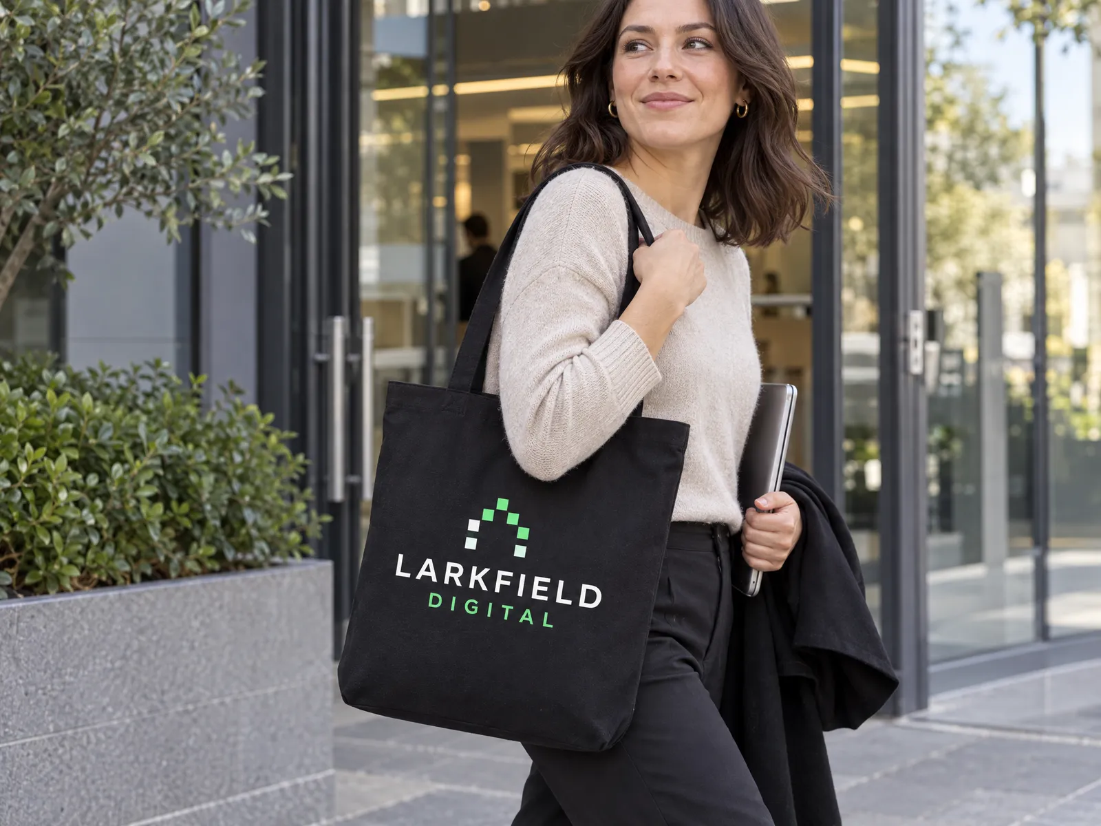 Black recycled canvas tote printed with a Larkfield Digital logo in white and mint green, carried out of an office